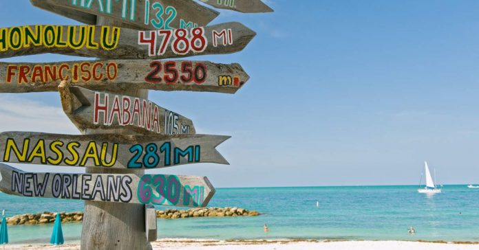 Sign post on beach in Key West Florida pointing to many destinations. aTRAVELthing.com
